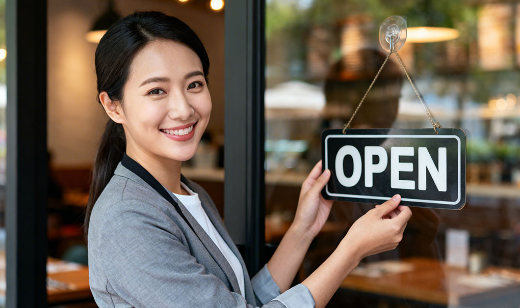 Restaurant owner turning an Open sign at the door of their newly opened Australian restaurant